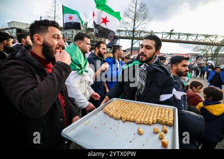 08. Dezember 2024, Nordrhein-Westfalen, Wuppertal: Süßigkeiten werden bei einer syrischen Kundgebung in Wuppertal verteilt. Foto: Christoph Reichwein/dpa Stockfoto