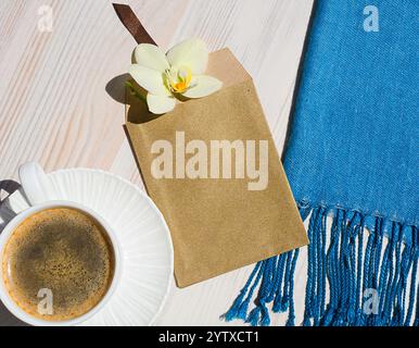 Eine Tasse Kaffee auf einem weißen Tisch. Umschlag mit Orchid. Romantischer Morgen. Datum der Einladung. Stockfoto