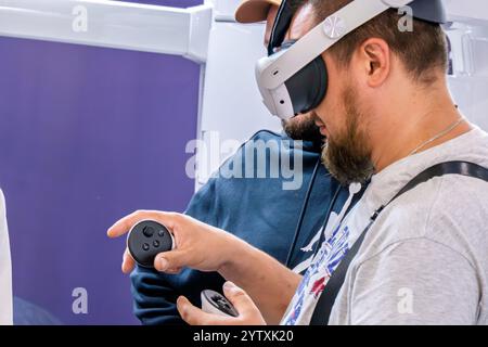 Kiew, Ukraine - 2. Oktober 2024: Bärtiger Mann in Virtual-Reality-Brille und Manipulatoren. Stockfoto