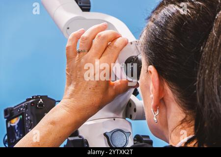 Eine Frau schaut in das Fernglas eines Zahnmikroskops Stockfoto