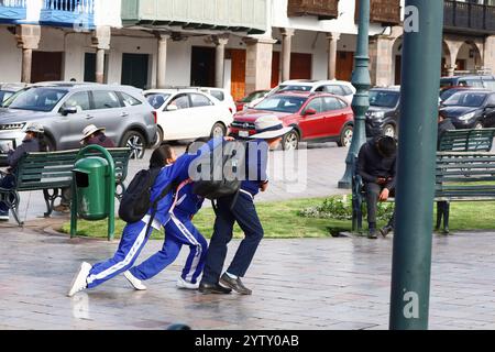 Cuzco, Peru - 9. Mai 2024: Zwei Mädchen und ein Junge gehen auf der Plaza de Arma zur Schule Stockfoto