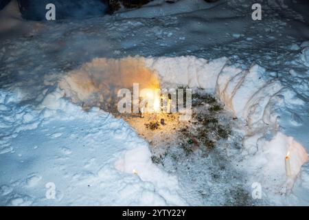 Feuerwerk und Kerzen brennen in verschneiten Böden während der Winterabendfeier. Stockfoto