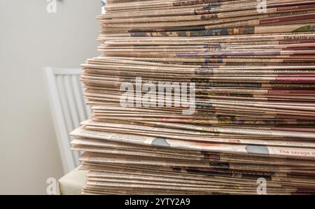 Großer Stapel von Geschäftszeitungen, die ordentlich auf einem Tisch angeordnet sind, mit gedruckten Artikeln und Schlagzeilen Stockfoto