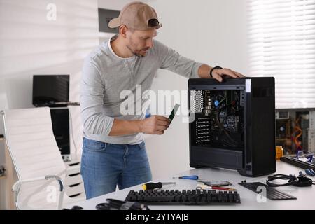 Mann, der einen neuen Computer am weißen Tisch zusammenbaut Stockfoto