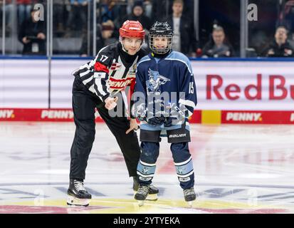 Hauptschiedsrichter Kilian Hinterdobler mit Puckkind Charlotte von den Speckers Dachau. GER, EHC Red Bull München vs. ERC Ingolstadt, Eishockey, DEL, 24. Spieltag, Saison 2024/2025, 08.12.2024. Foto: Eibner-Pressefoto/Heike Feiner Stockfoto