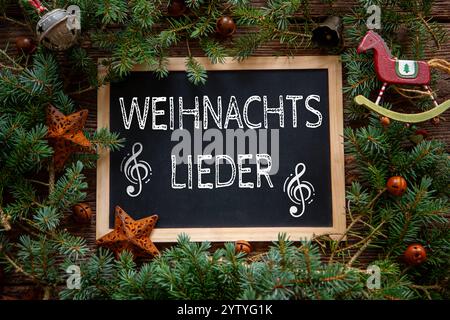 Bayern, Deutschland - 8. Dezember 2024: Ein symbolisches Bild für Weihnachtslieder, dargestellt auf einer dekorativen Tafel mit musikalischen Symbolen und Weihnachtsdekorationen. Eine Referenz zu traditionellen Liedern wie Stille Nacht und die festliche Atmosphäre der Adventszeit. FOTOMONTAGE *** ein Symbolbild für Weihnachtslieder, dargestellt auf einer dekorativen Tafel mit musikalischen Symbolen und weihnachtlichem Schmuck. Ein Verweis auf traditionelle Lieder wie Stille Nacht und die festliche Atmosphäre der Adventszeit. FOTOMONTAGE Stockfoto