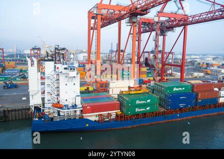 Weitwinkelansicht von Portalkranen, die schwere Frachtcontainer vom Schiff zum Kai transportieren, unter Verwendung der Lo-Lo-Anlage im Hafen von Dublin in Irland. Stockfoto