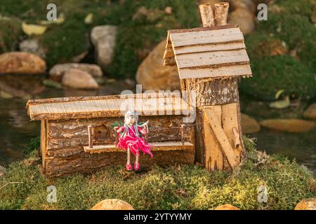 Handgefertigtes Spielzeughaus einer Fee im Stamm eines Baumes zur weihnachtsdekoration, kleines hölzernes Feenhaus Stockfoto