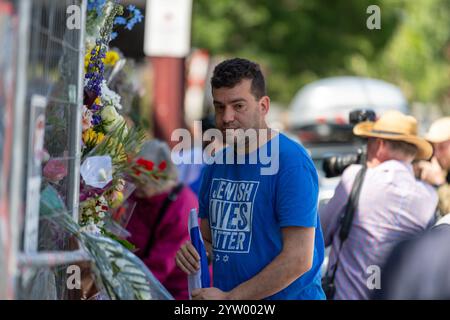 Ein Mann mit einem T-Shirt „Jewish Lives Matter“ hält an, nachdem er Blumen in den temporären Zaun der verbrannten Adass Israel Synagoge gelegt hat, nach einer Kundgebung, die Gerechtigkeit und Einheit in Melbourne, Australien, forderte. Die jüdische Gemeinde in Melbourne veranstaltete eine Kundgebung in der Nähe der Adass Israel Synagoge in Ripponlea, nachdem das Gebäude bei einem angeblichen Brandanschlag von Männern in schwarz gekleidet Anfang dieser Woche in Brand gesetzt wurde. Die Demonstration verurteilte den Antisemitismus und forderte Gerechtigkeit, wobei die Teilnehmer die Notwendigkeit von Einheit und Toleranz betonten. Die Synagoge, ein Eckpfeiler des jüdischen Lebens in der Gegend, die Führer haben p Stockfoto