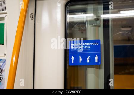 Ein Schild an einer Zugtür mit der Aufschrift 'Ateno Reservado' auf Spanisch. Das Schild ist blau und weiß und zeigt ein Bild einer Person mit einem Stock Stockfoto