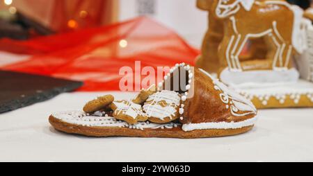 Ein Hausschuh mit einer Menge kleiner Kekse, hergestellt aus essbarem Lebkuchen und mit Zuckerglasur dekoriert. Eine süße fette Dekoration auf dem Weihnachtstisch Stockfoto