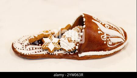 Ein Hausschuh mit einer Menge kleiner Kekse, hergestellt aus essbarem Lebkuchen und mit Zuckerglasur dekoriert. Eine süße fette Dekoration auf dem Weihnachtstisch Stockfoto