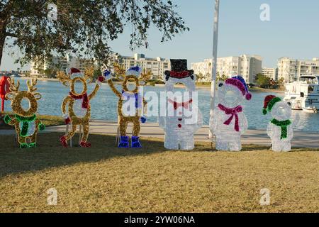 Breiter gerahmter Blick auf mehrere rote, weiße und grüne Weihnachtsfotofiguren. Stuhl und Zuckerstangen auf dem roten Sitz. Weißes Boot im Rahmen mit Stockfoto