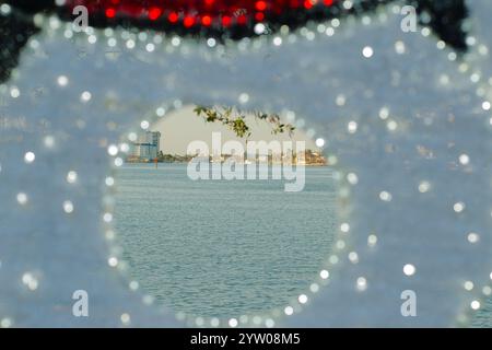 Breiter kreisförmiger Blick durch einen rot-weißen Schneemannsfotostand. Rahmen mit Boca Ciega Bay und Gebäude im hinteren St. Pete Stockfoto