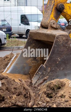 Ein hellgelber Bagger gräbt aktiv ein großes Loch tief in den Boden und demonstriert seine beeindruckenden Fähigkeiten Stockfoto