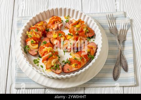 Uunimakkara, gebacken im Ofen Würstchen mit Käse, Tomaten, Senf in Backform auf weißem Holztisch mit Gabeln, finnisches klassisches Rezept Stockfoto