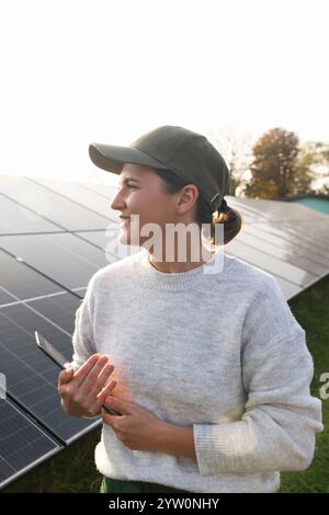 Farmerin mit digitalem Tablet auf einem modernen Bauernhof mit Solarpaneelen. Stockfoto