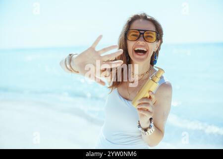 Lächelnde elegante 40-jährige Frau am Strand mit lichtschutzfaktor. Stockfoto