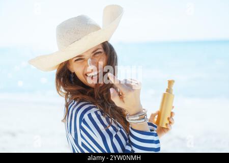 Lächelnde, moderne Frau mittleren Alters am Meer mit spf. Stockfoto