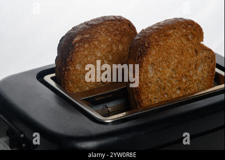 Scheiben VollkornbrotGoldener brauner Toast, der morgens aus einem eleganten Toaster auftaucht. Stockfoto