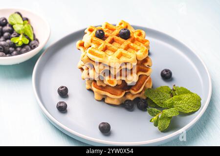 Zwei Stapel frisch gebackener belgischer oder Wiener Waffeln mit Blaubeeren und Minze auf einem blauen Teller. Hochwertige Fotos Stockfoto