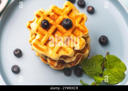 Zwei Stapel frisch gebackener belgischer oder Wiener Waffeln mit Blaubeeren und Minze auf einem blauen Teller. Hochwertige Fotos Stockfoto