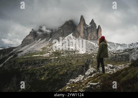 Eine Person steht auf einem zerklüfteten und felsigen Hügel und genießt den atemberaubenden Blick auf einen majestätischen Berg in der Ferne Stockfoto