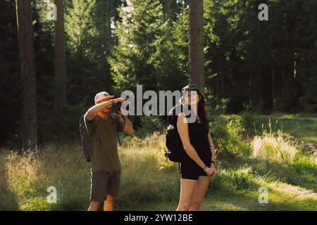 Ein Mann fotografiert gerade eine Frau, die sich im ruhigen Wald befindet und einen Moment in natürlicher Schönheit festnimmt Stockfoto
