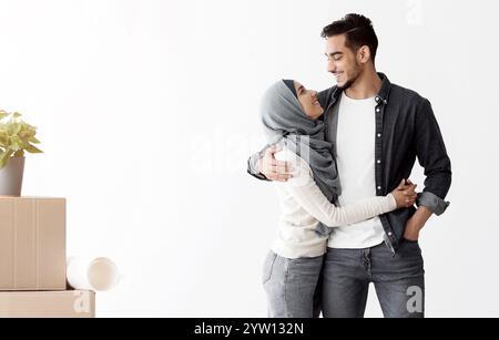 Liebevolles muslimisches Paar, das in leerer Wohnung unter den Vorräten steht Stockfoto