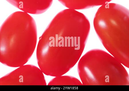 Eine Nahaufnahme kleiner, leuchtend roter Erdbeertomaten auf einem sauberen weißen Hintergrund. Die glatte und helle Haut der Tomaten. Frisches Gemüse. Stockfoto