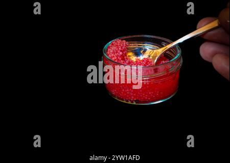 Roter Lumpfish Reh in einem Glasgefäß und eine Hand mit einem Löffel Stockfoto