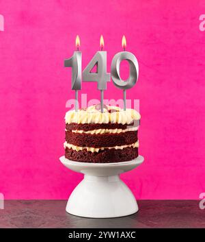 Roter Samtkuchen - Geburtstagsnummer 140 auf rosafarbenem Hintergrund. Stockfoto