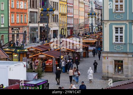 Breslau, Polen - 4. Dezember 2024: Blick auf den lebhaften Weihnachtsmarkt mit festlichen Holzständen, farbenfrohen historischen Gebäuden und Besuchern Stockfoto