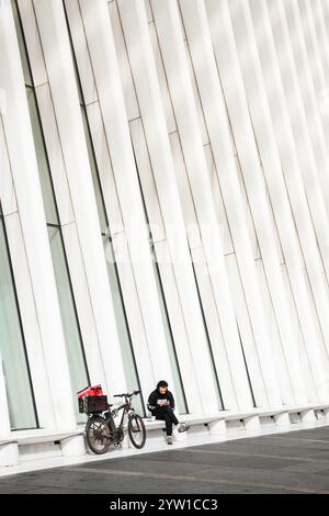 NEW YORK CITY – 18. MAI 2024: Ein einsamer Fahrer ruht mit seinem Fahrrad unter der imposanten Form des Oculus, dem architektonischen Wahrzeichen der neuen World Tra Stockfoto