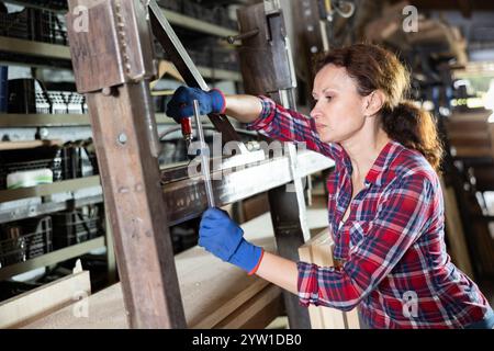 Werkstattangestellte steht neben Eisenschienen von Werkstücken, misst die Länge Stockfoto