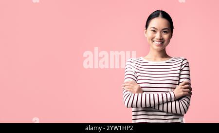 Porträt Einer Jungen, Selbstbewussten, Lächelnden Asiatischen Frau, Die Mit Gefalteten Armen Steht Stockfoto