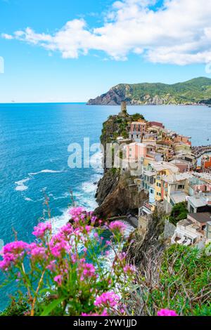 Erleben Sie die atemberaubende Küste von Cinque Terre, wo sich farbenfrohe Häuser an felsigen Klippen Klammern, während Wellen gegen die Küste krachen. Vernazza Italien in Stockfoto