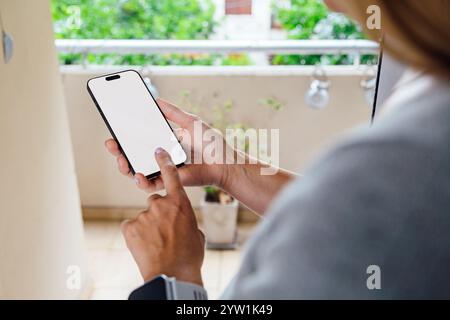 Nahaufnahme einer Frau, die zu Hause ein Mobiltelefon mit leerem Bildschirm benutzt. Foto für Modell ideal zum Platzieren Ihres Designs. Stockfoto