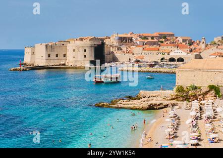Die Wellen schlagen sanft gegen die Sandküste von Dubrovnik Kroatien, während die Besucher die warme Sonne und das klare Wasser im Sommer genießen Stockfoto