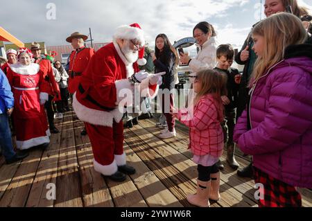 Richmond, Kanada. Dezember 2024. Ein als Weihnachtsmann gekleideter Mann interagiert am 8. Dezember 2024 mit einem Kind an der Steveston Fisherman's Wharf in Richmond, British Columbia, Kanada. Die Ankunft des Weihnachtsmanns mit dem Boot fand hier am Sonntag statt, um die Weihnachtszeit zu beginnen. Quelle: Liang Sen/Xinhua/Alamy Live News Stockfoto