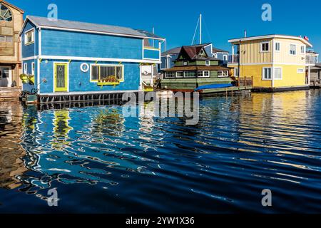 Eine Reihe von bunten Häusern sitzt auf dem Wasser, von denen eines ein gelbes Haus ist. Das Wasser ist ruhig und die Häuser spiegeln sich im Wasser. Die sce Stockfoto
