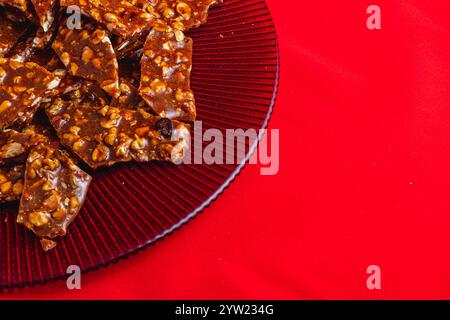 Hausgemachte Zuckerkekse mit Nüssen auf einem glänzenden roten Teller Stockfoto