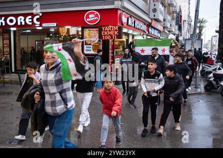 Izmir, Türkei. Dezember 2024. Eine syrische Gruppe marschiert mit der Flagge der syrischen Nationalarmee. Der Sturz der Regierung von Baschar al-Assad mit dem Einzug von Hayat Tahrir al-Sham nach Damaskus hat Millionen syrischer Flüchtlinge, die in der Türkei leben, auf die Straße gebracht. Die in Izmir lebenden Syrer gingen auf die Straße und zeigten ihre Freude. Quelle: SOPA Images Limited/Alamy Live News Stockfoto