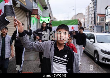 Izmir, Türkei. Dezember 2024. Eine syrische Gruppe marschiert mit der Flagge der syrischen Nationalarmee. Der Sturz der Regierung von Baschar al-Assad mit dem Einzug von Hayat Tahrir al-Sham nach Damaskus hat Millionen syrischer Flüchtlinge, die in der Türkei leben, auf die Straße gebracht. Die in Izmir lebenden Syrer gingen auf die Straße und zeigten ihre Freude. Quelle: SOPA Images Limited/Alamy Live News Stockfoto