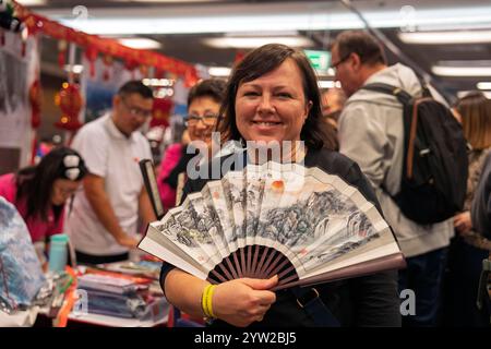 Warschau, Polen. Dezember 2024. Eine Frau kauft einen Fan am chinesischen Stand während des 17. Internationalen Wohltätigkeitsbasars in Warschau, Polen, 8. Dezember 2024. Mehr als 50 Botschaften in Polen nahmen an der Veranstaltung Teil, wobei der Verkaufserlös an 16 polnische Wohltätigkeitsorganisationen gespendet wurde. Quelle: Xia Yuanyi/Xinhua/Alamy Live News Stockfoto