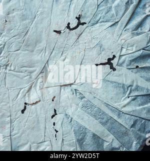 Eine künstlerische Nahaufnahme aus zerknittertem Papier mit ausdrucksstarken schwarzen Tintenspritzern, die eine einzigartige, faszinierende Textur schaffen Stockfoto