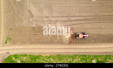 Über der Draufsicht des Traktors als Zugmaschine, das Ackerfeld scheuert, zerfetzt die Erde, um den Boden für das Anpflanzen neuer Früchte in der nächsten Saison vorzubereiten. Stockfoto