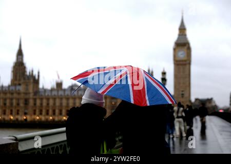 London, Großbritannien. Dezember 2024. Die Leute laufen am 8. Dezember 2024 auf der Westminster Bridge in London, Großbritannien. Zehntausende von Häusern wurden ohne Strom gelassen, Bahn- und Luftverkehr wurden gestört und Sportveranstaltungen in ganz Großbritannien wurden am Samstag abgesagt, als der Sturm Darragh zuschlug. Quelle: Li Ying/Xinhua/Alamy Live News Stockfoto