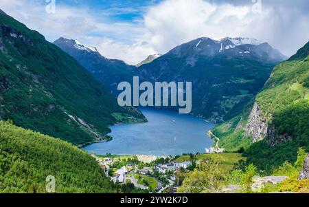 Ein malerischer Blick auf einen norwegischen Fjord, umgeben von majestätischen grünen Bergen. Das Wasser ist ruhig und blau und der Himmel ist klar. Geiranger Fjord Norwegen in Stockfoto