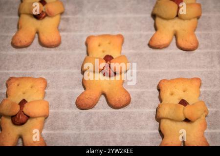 Entzückende bärenförmige, hausgemachte Zuckerkekse, die eine Mandel in den Pfoten auf einem Backblech halten, frisch aus dem Ofen, Weihnachtsbacken Stockfoto